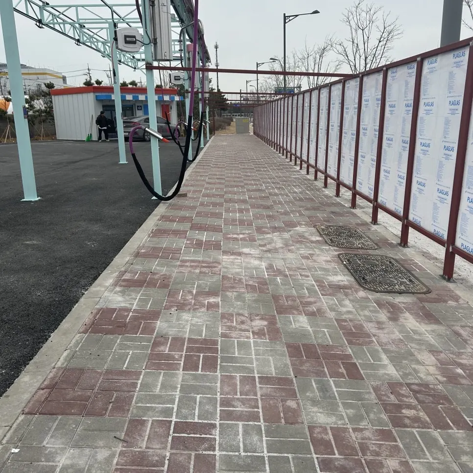 펜스 옆 벽돌 보행로의 차량 스토퍼